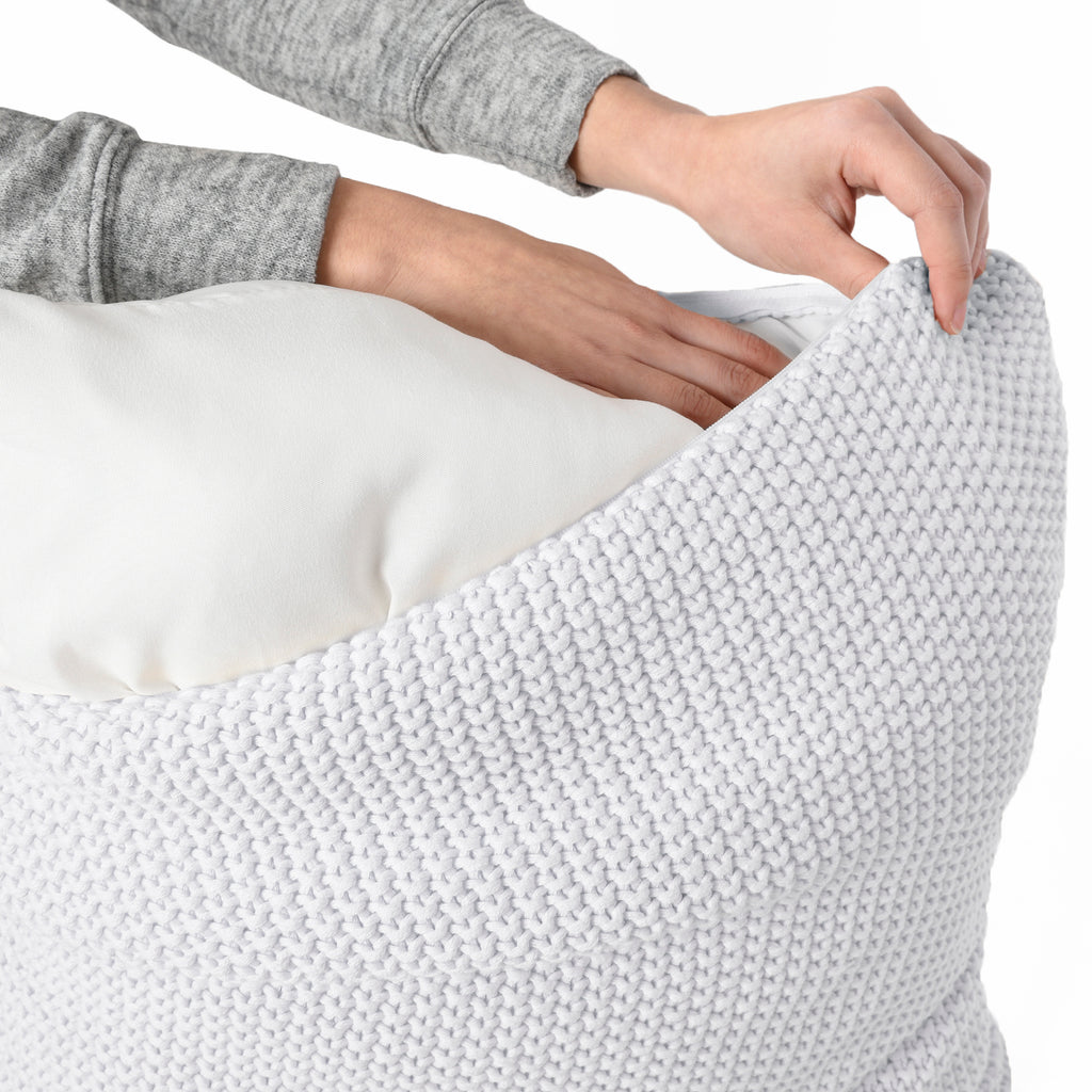 A pillow cover being placed on  a 20 by 20 inch pillow insert